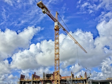 yellow crane under blue sky and white clouds during daytime