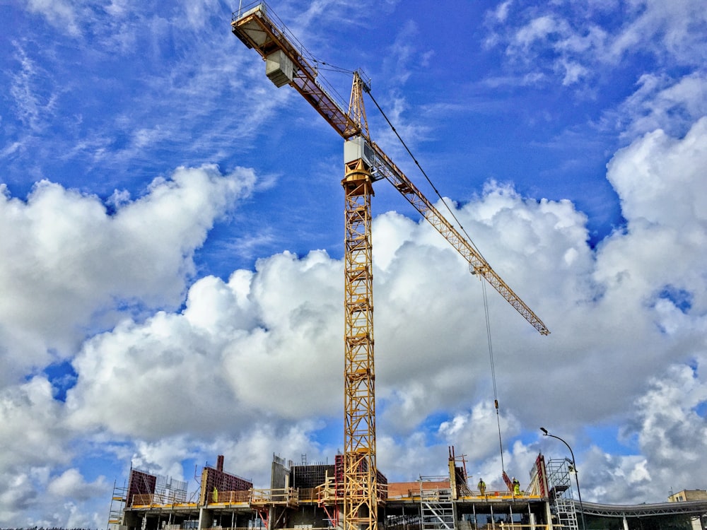 yellow crane under blue sky and white clouds during daytime