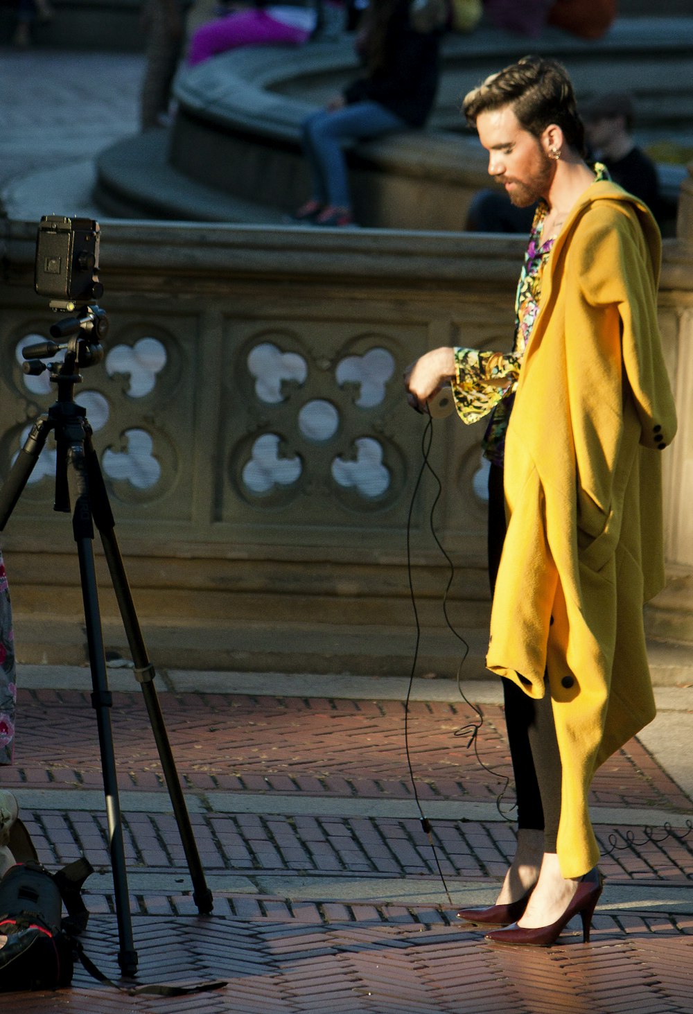 woman in yellow robe standing beside black camera tripod
