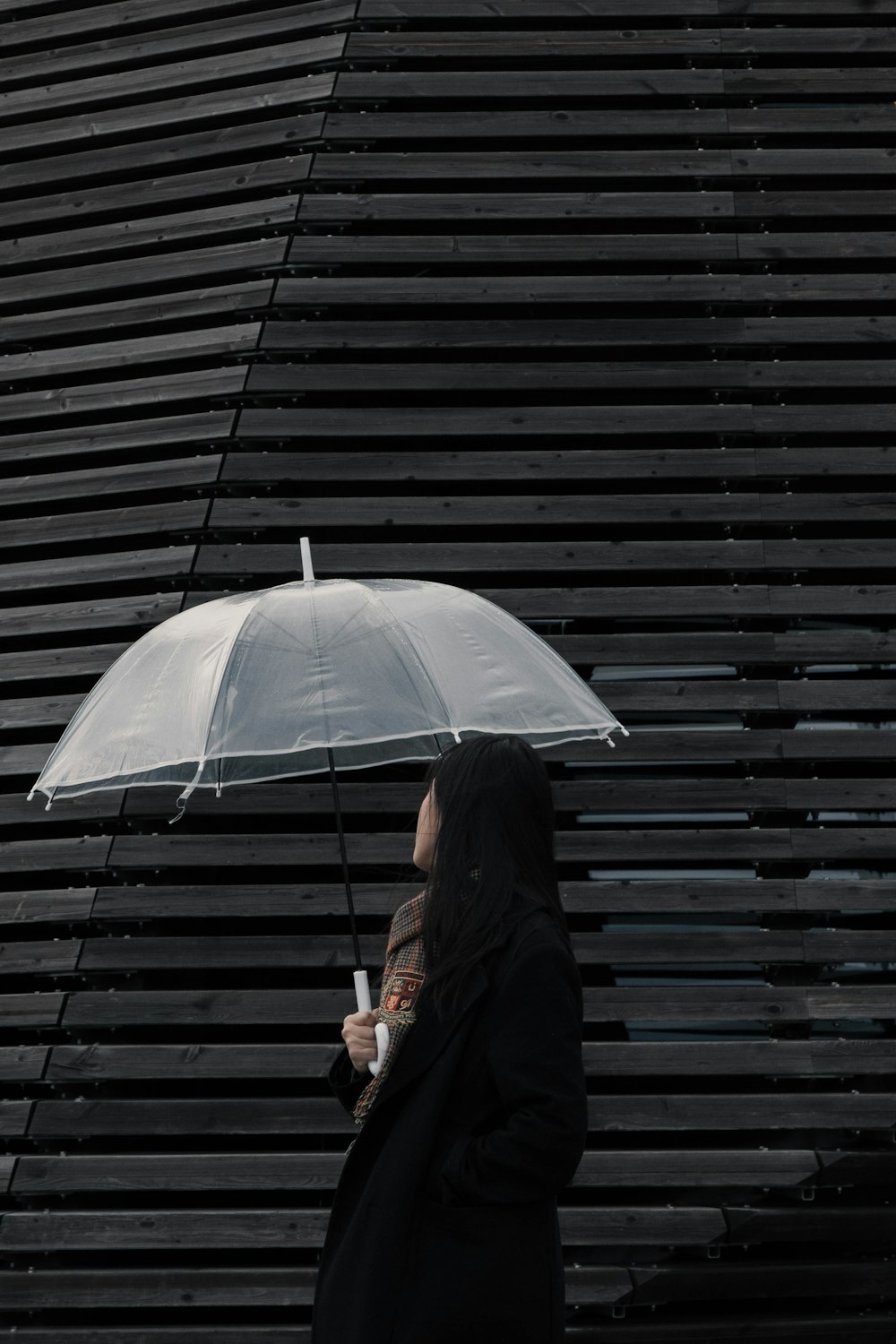 woman in black coat holding white umbrella
