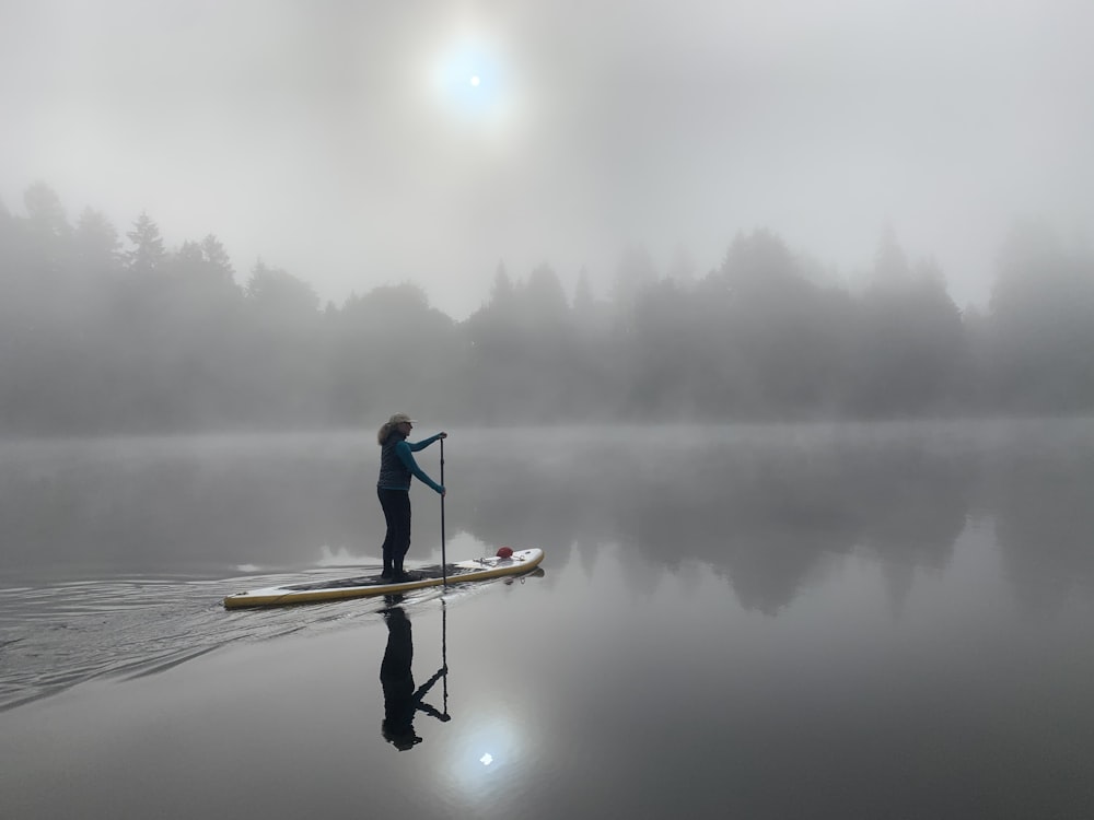 Mann in roter Jacke fährt bei Nebel auf dem Boot auf dem See