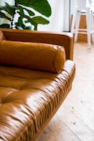 brown leather couch on white ceramic floor tiles