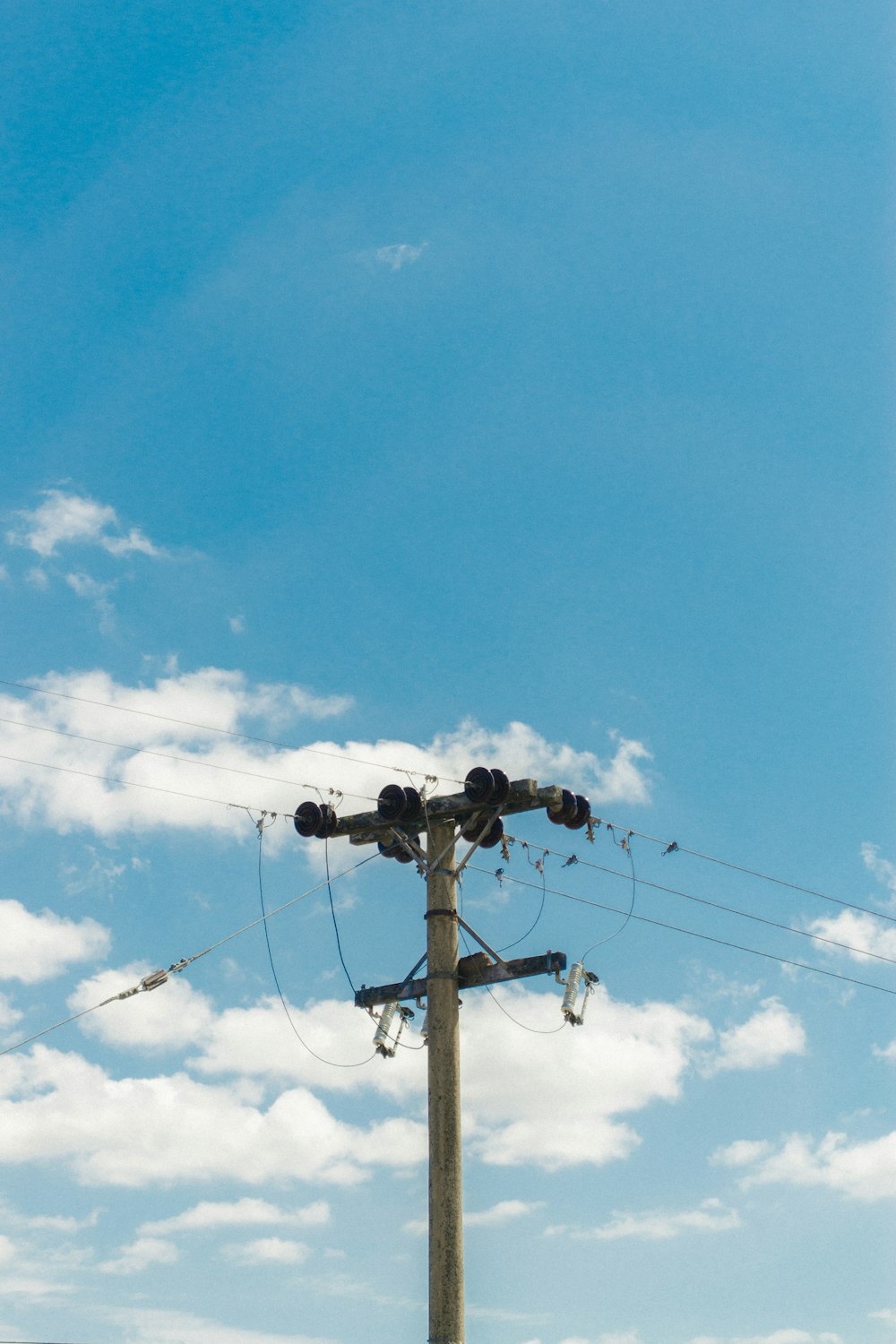 brown wooden electric post under blue sky during daytime