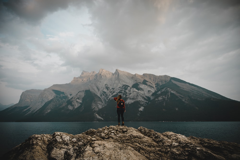 person standing on rock near body of water during daytime