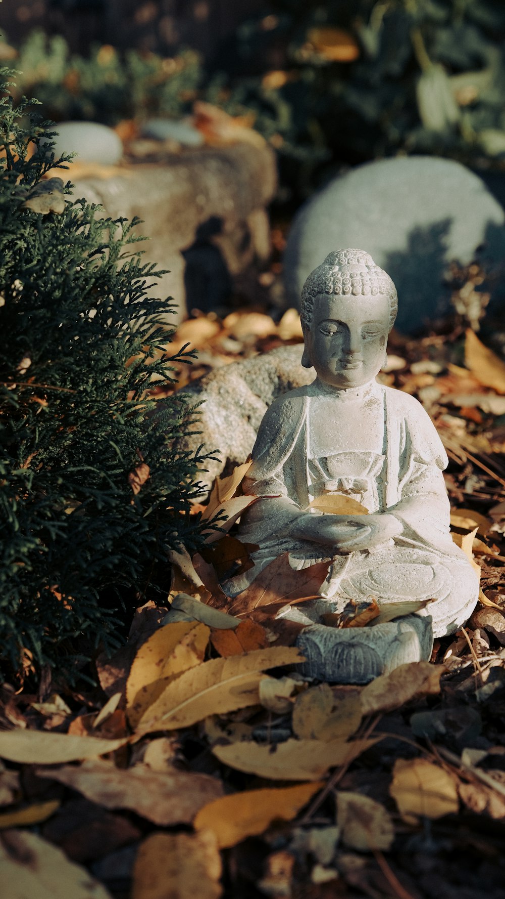 Figura de Buda de cerámica blanca sobre hojas secas marrones