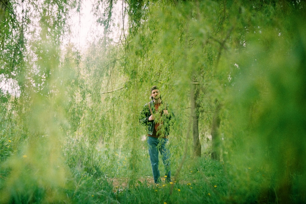 femme en jean bleu debout sur le champ d’herbe verte pendant la journée