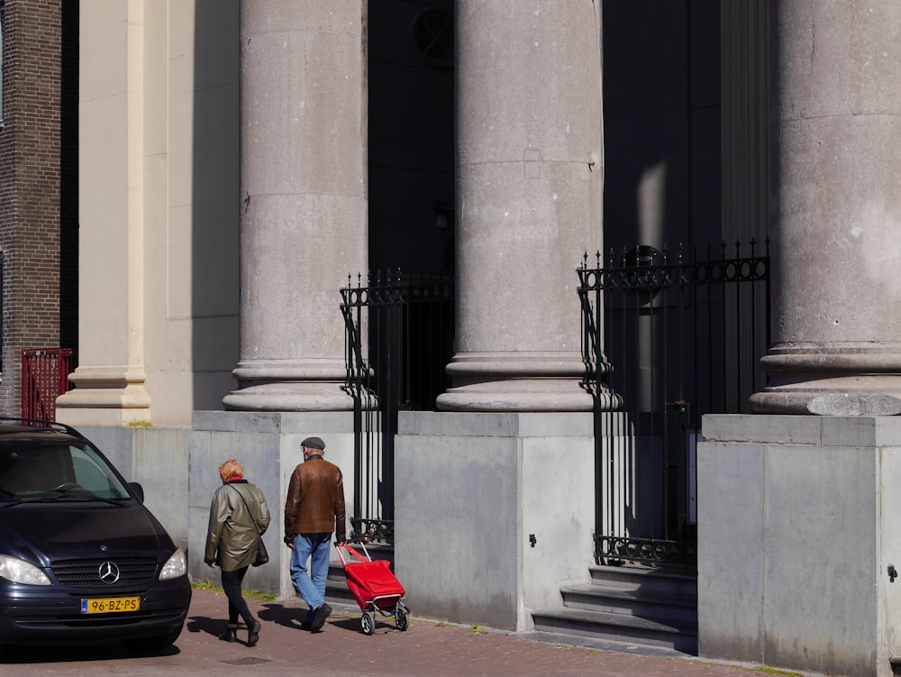 man in orange shirt sitting on red and black motorcycle near black car during daytime