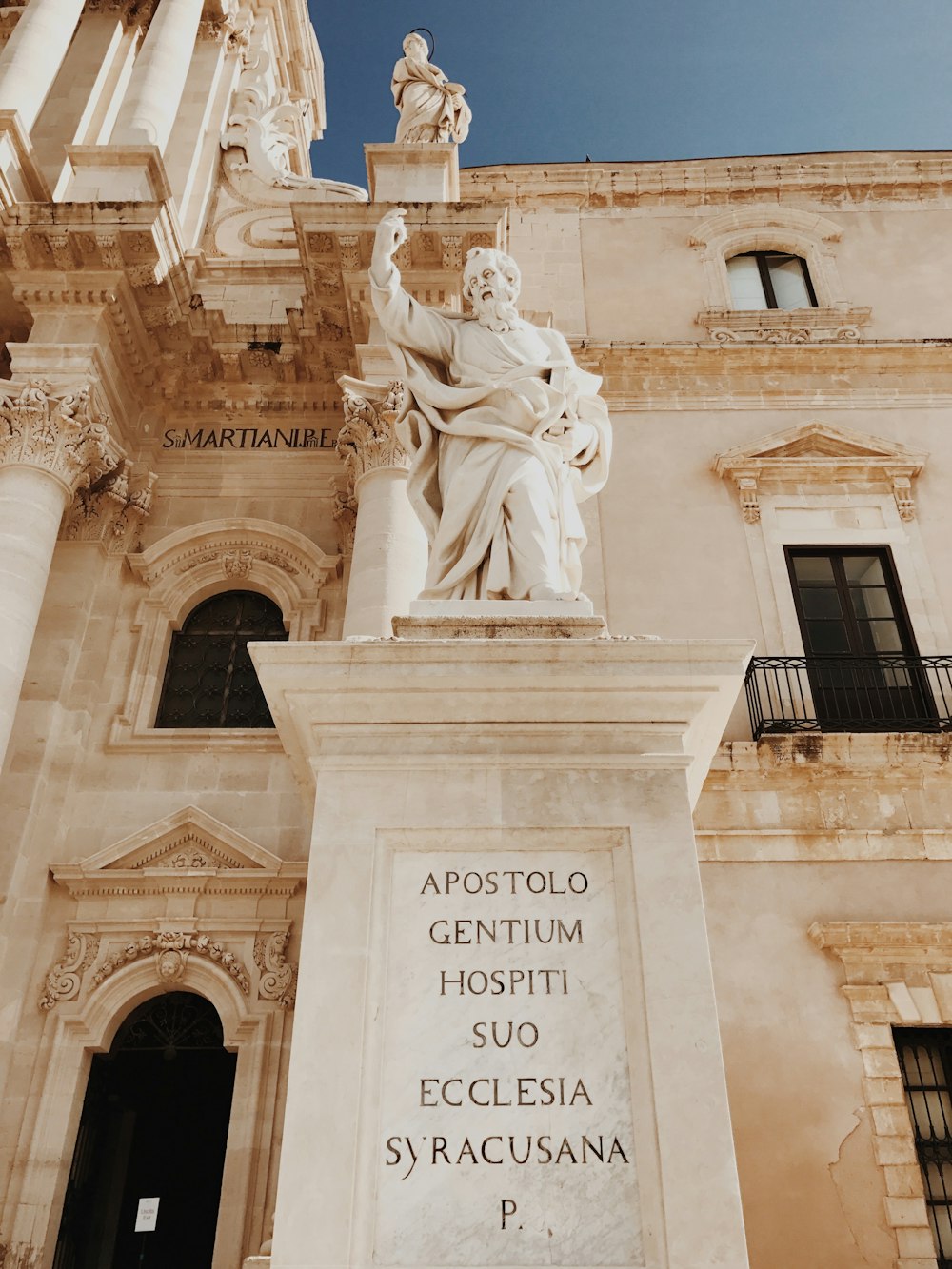 a statue of a man holding a book in front of a building