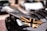 A close-up of a car wing with a Union Jack design in black and gold. The background is blurred, showing other cars in a parking lot.