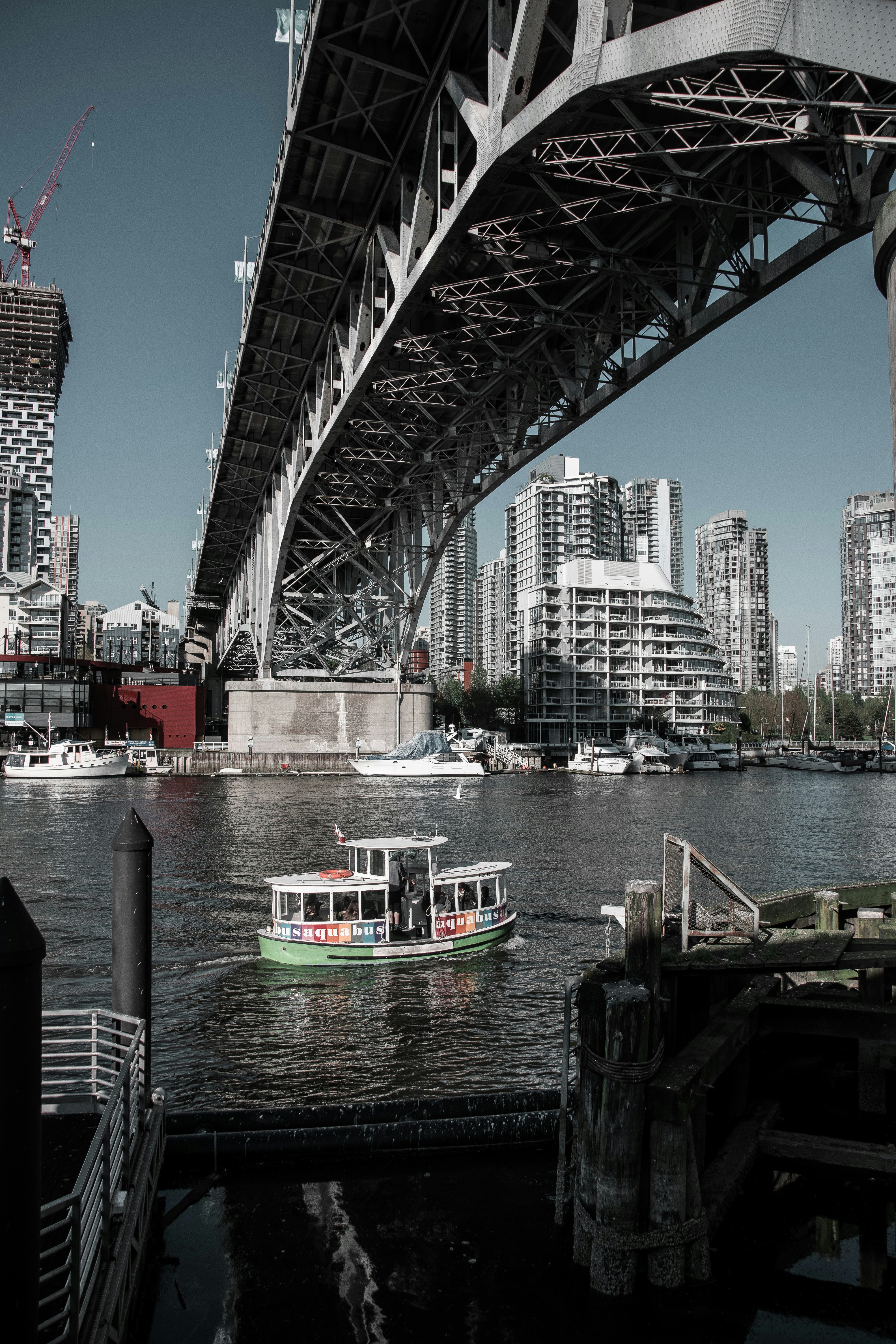 weißes und rotes Boot tagsüber auf dem Wasser unter der Brücke