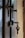 A close-up view of a door with two metallic locks. One of the locks contains a key with a simple design, slightly bent at an angle. The door appears to be made of dark wood, and there is a muted, blurry background visible through a gap in the door.