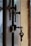 A close-up view of a door with two metallic locks. One of the locks contains a key with a simple design, slightly bent at an angle. The door appears to be made of dark wood, and there is a muted, blurry background visible through a gap in the door.