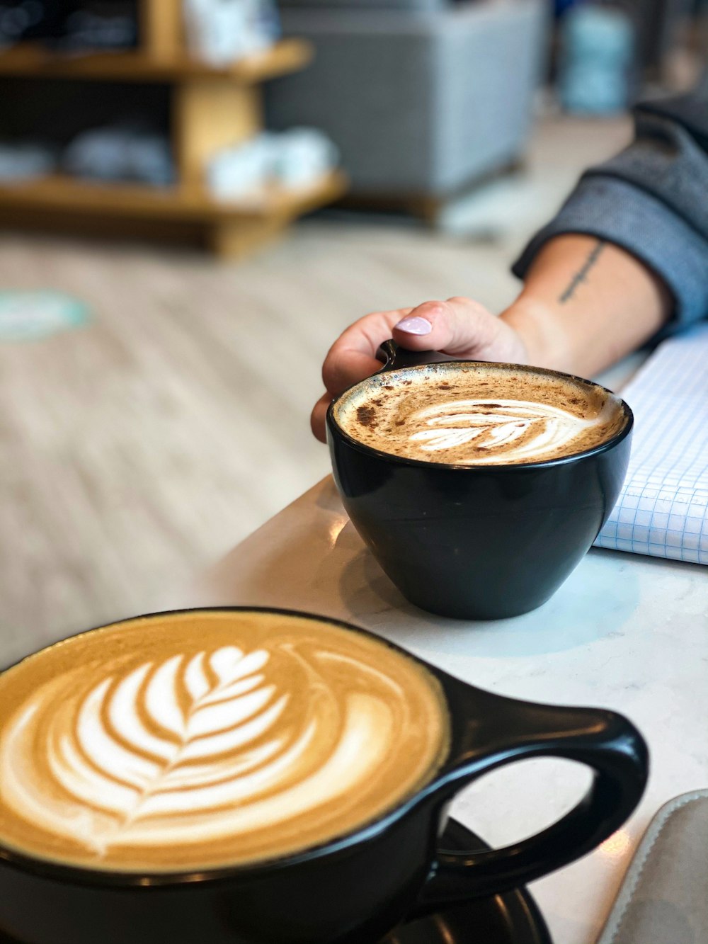 person holding black ceramic mug with cappuccino