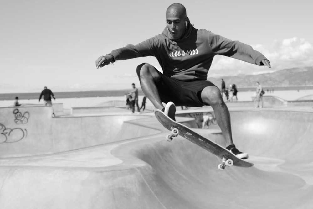 Mann in schwarzem Hoodie und schwarzer Hose auf Skateboard