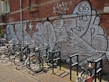 A row of colorful urban bikes lined up in front of a graffiti wall