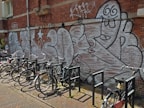 A row of colorful urban bikes lined up in front of a graffiti wall