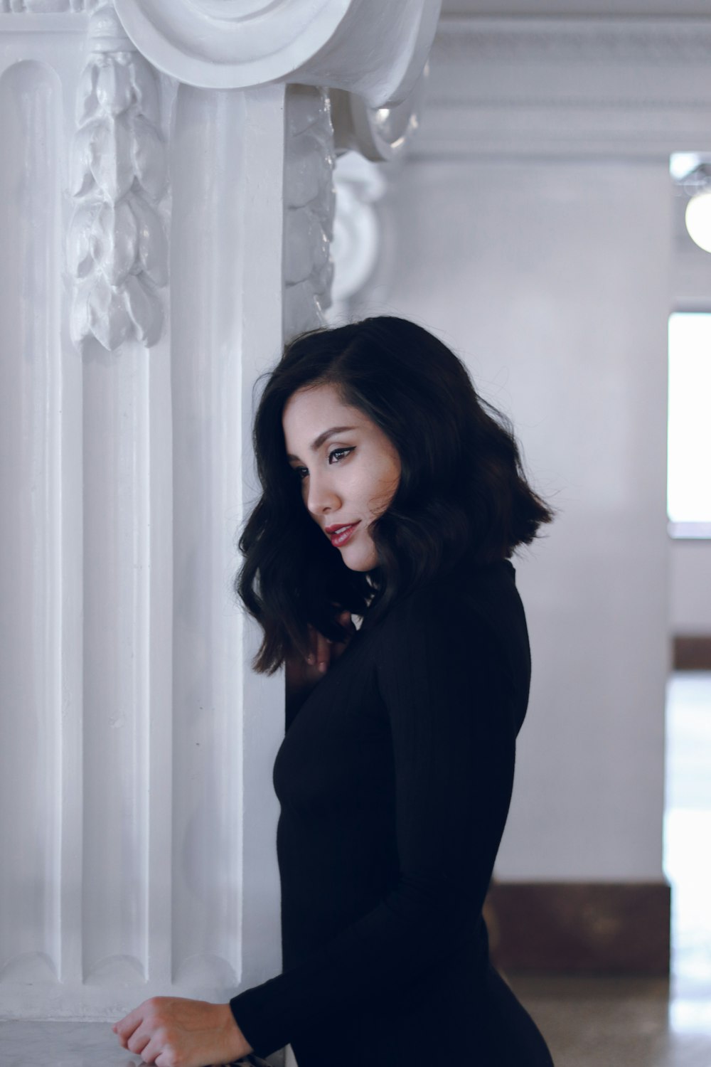 woman in black long sleeve shirt standing near white curtain