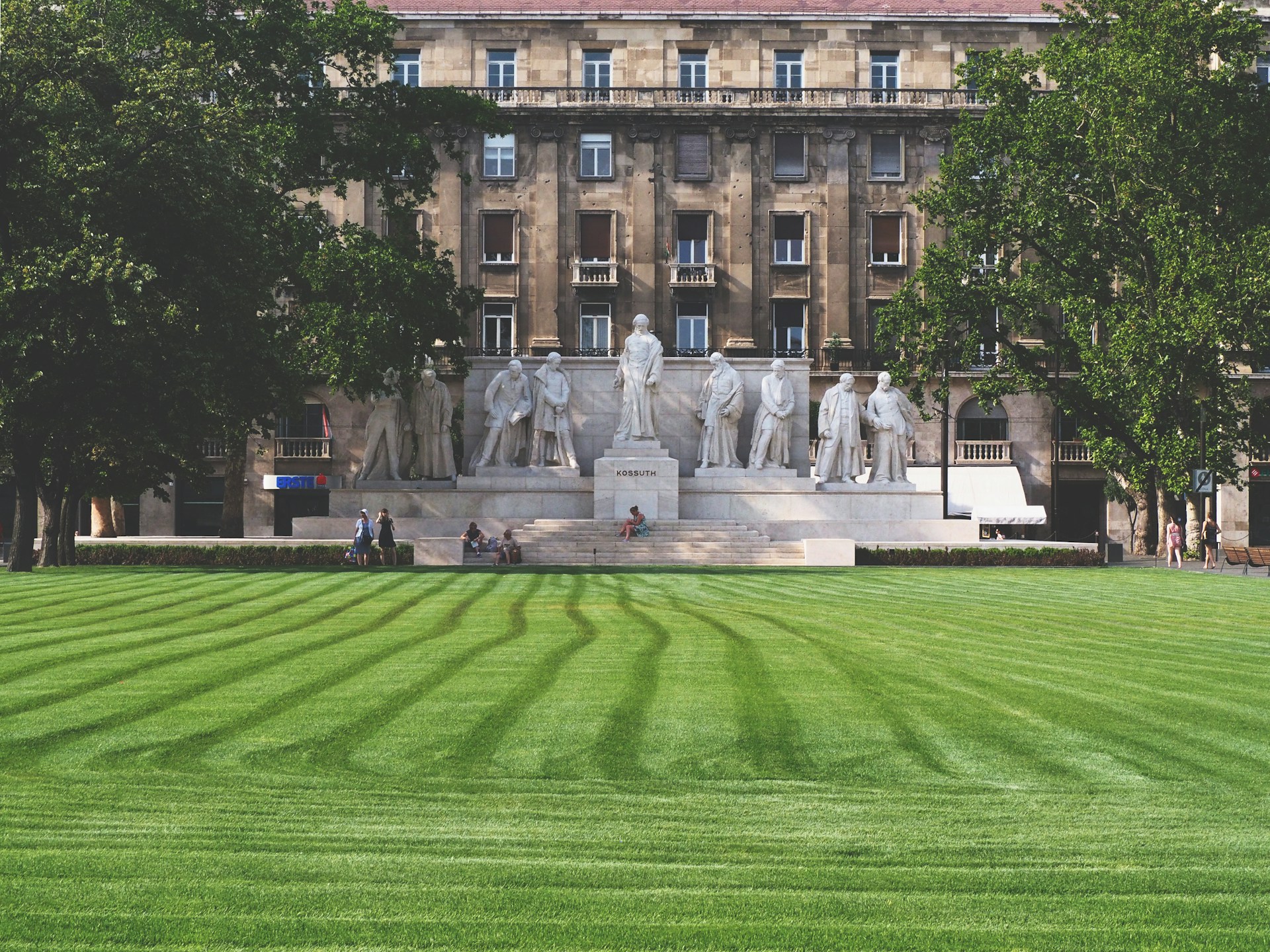 people walking on green grass field near brown concrete building during daytime