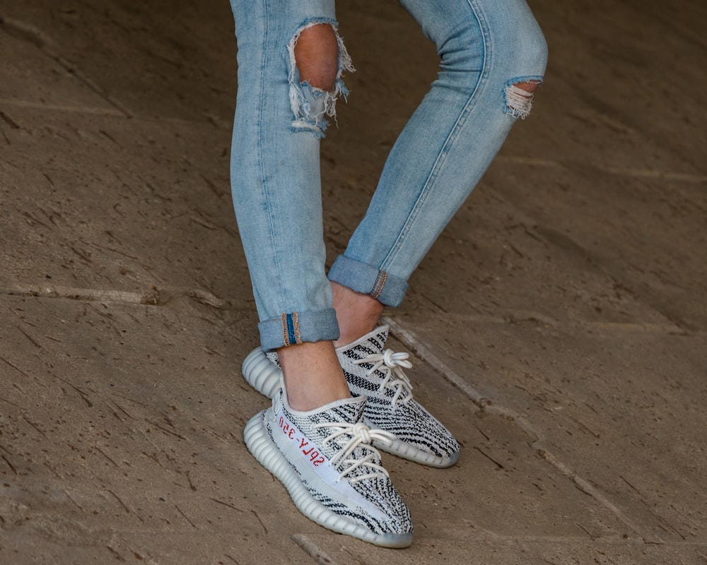 person in blue denim jeans and white sneakers