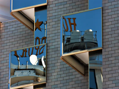 A freshly cleaned large storefront window reflecting a bright blue sky with maroon and gold accents visible inside.