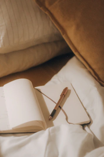A notebook and pen resting on a cozy blanket, inviting reflection and personal growth.