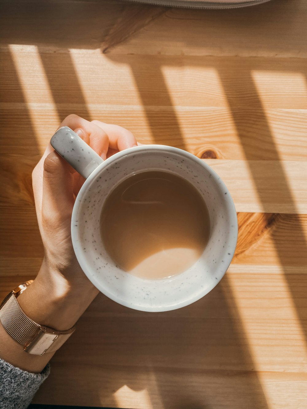 person holding white ceramic mug with black liquid