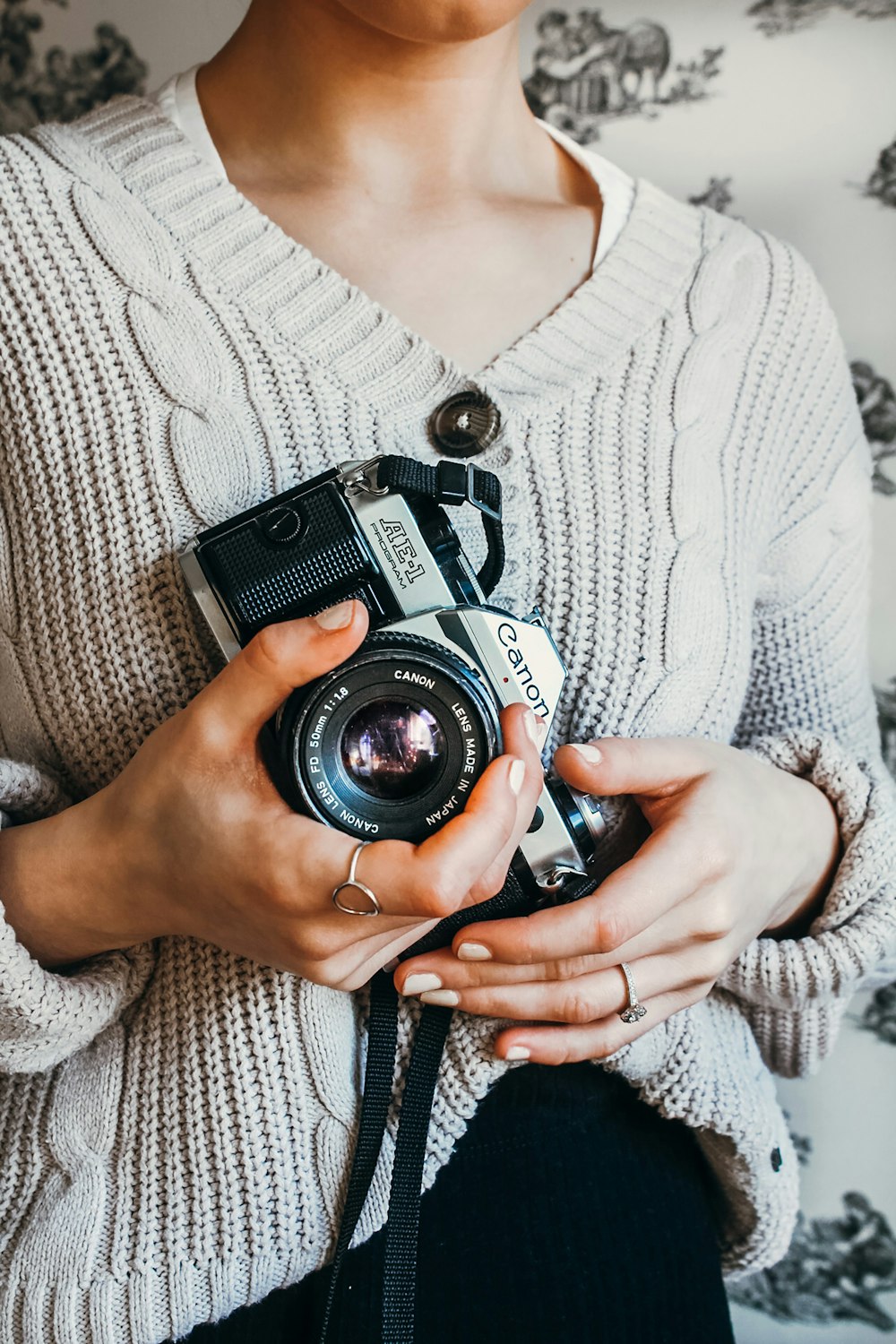 woman in white knit sweater holding black and silver dslr camera