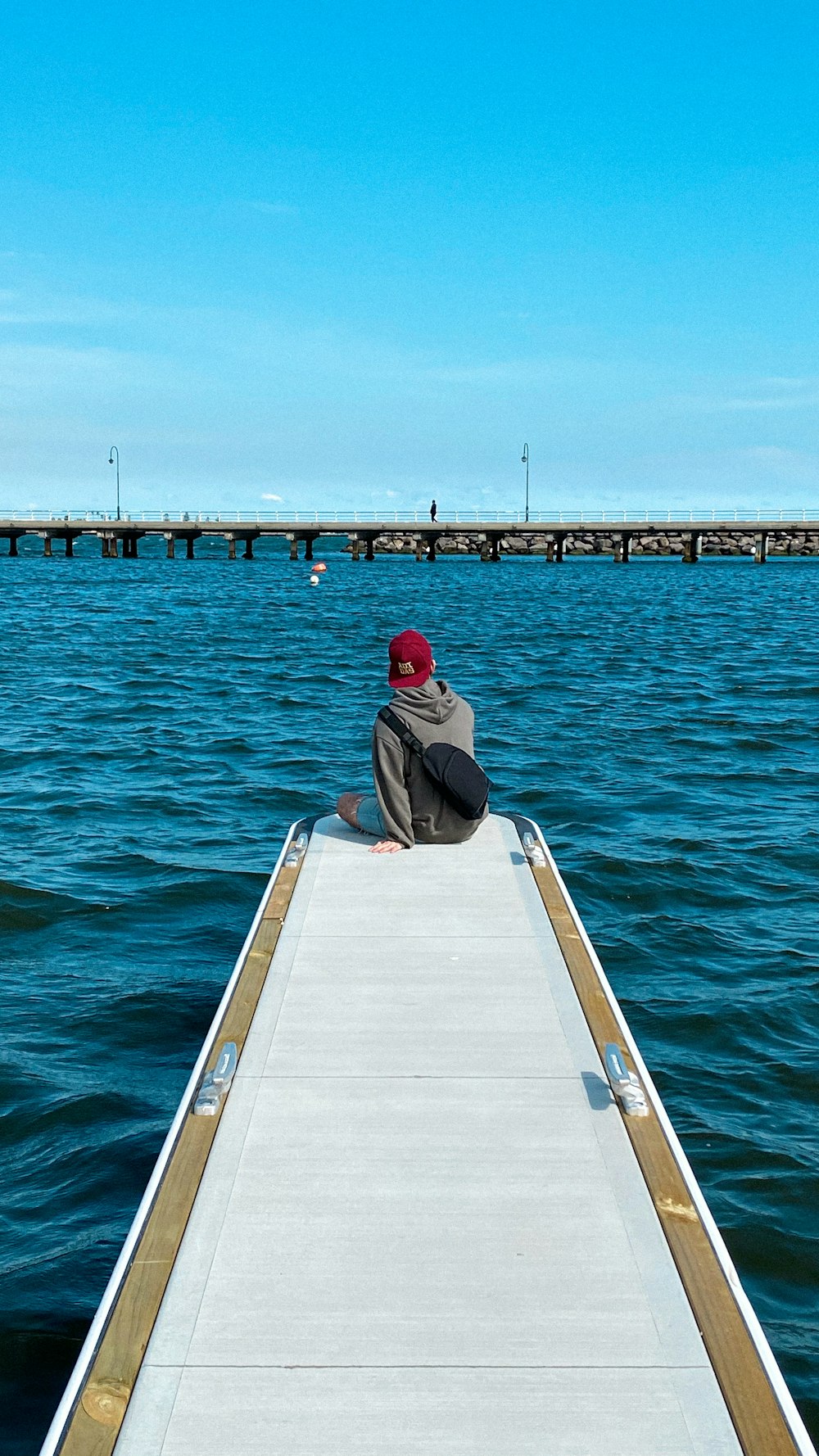 man in black t-shirt and blue denim jeans sitting on dock during daytime