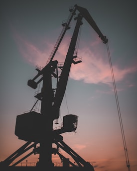 A security camera overlooking a heavy-duty crane in operation at dusk