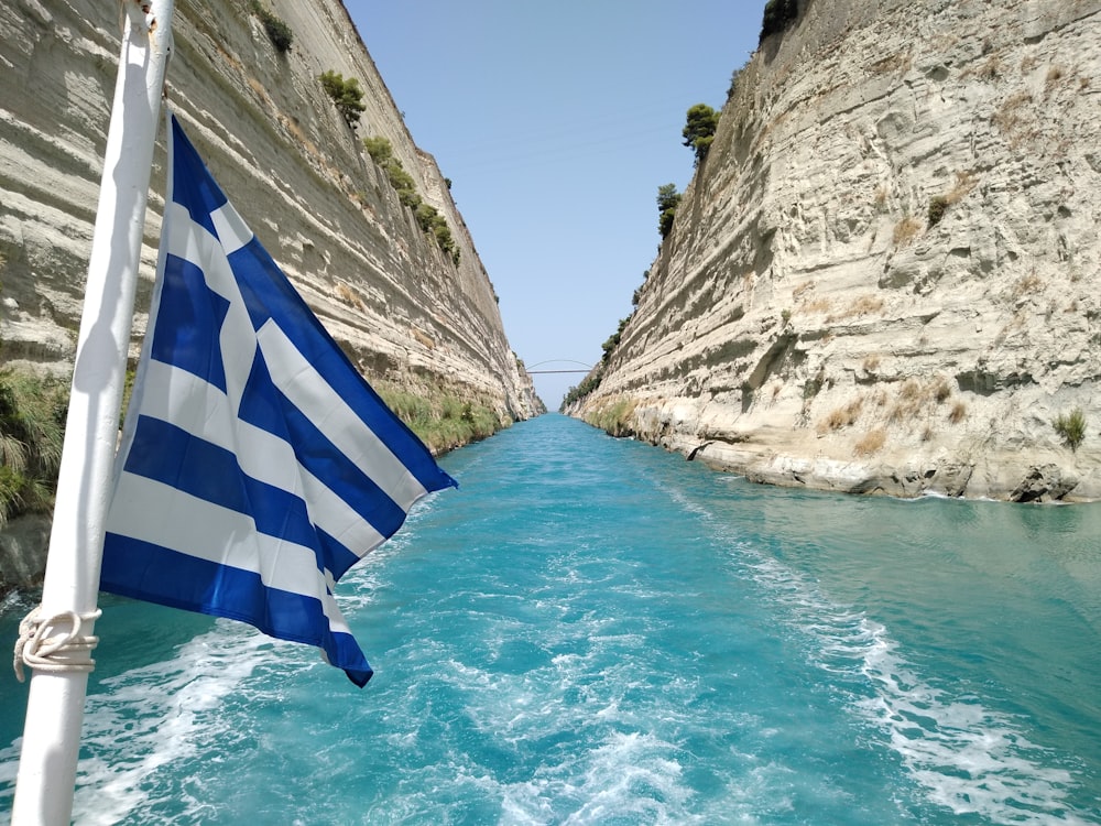 blue and white striped flag on rock formation near body of water during daytime