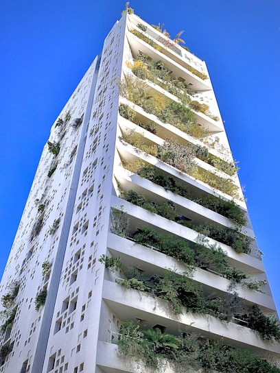 A vibrant mixed-use commercial building with lush greenery integrated into the architecture on a sunny day.