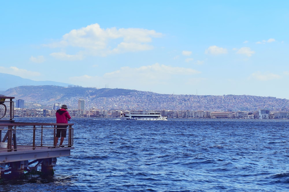 man in red shirt sitting on red boat during daytime