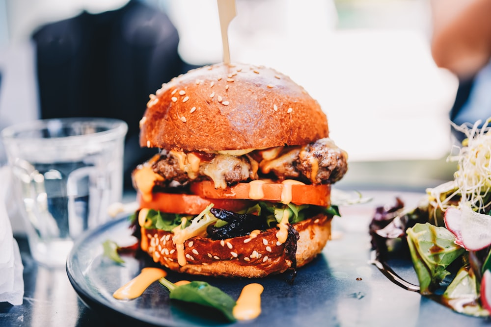 burger with lettuce and cheese on black ceramic plate