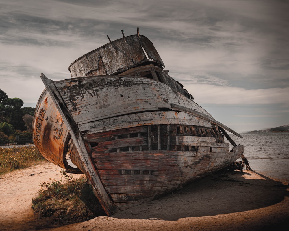 brown and gray ship on brown sand under gray cloudy sky