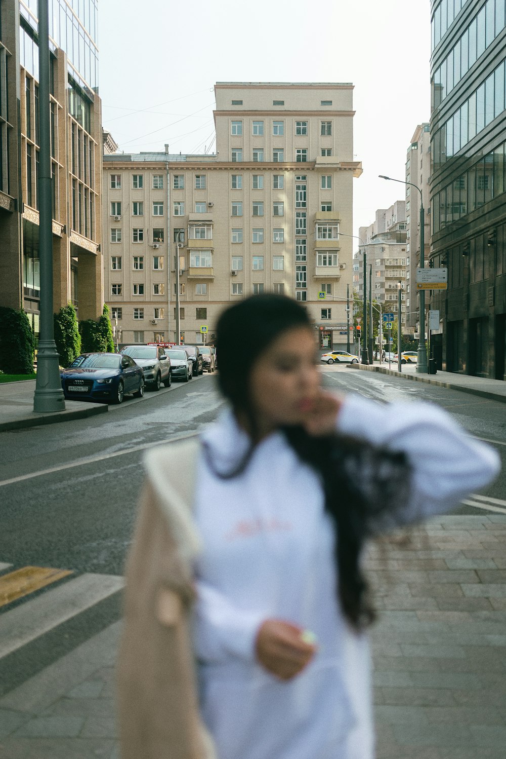 woman in white jacket standing on sidewalk during daytime