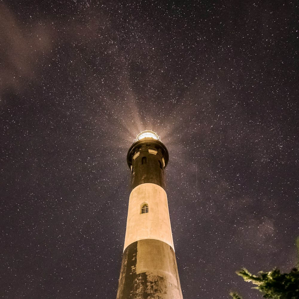 white and black lighthouse under starry night