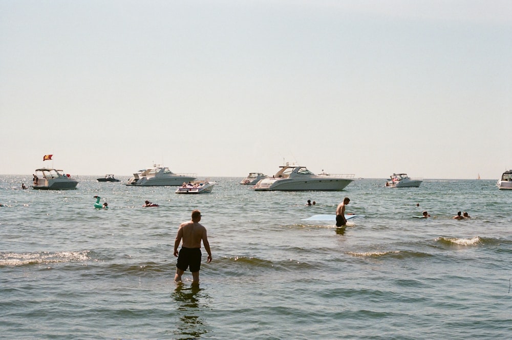 man in black wet suit standing on sea shore during daytime