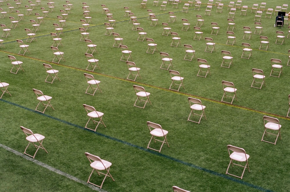 Sillas plegables blancas en un campo de césped verde