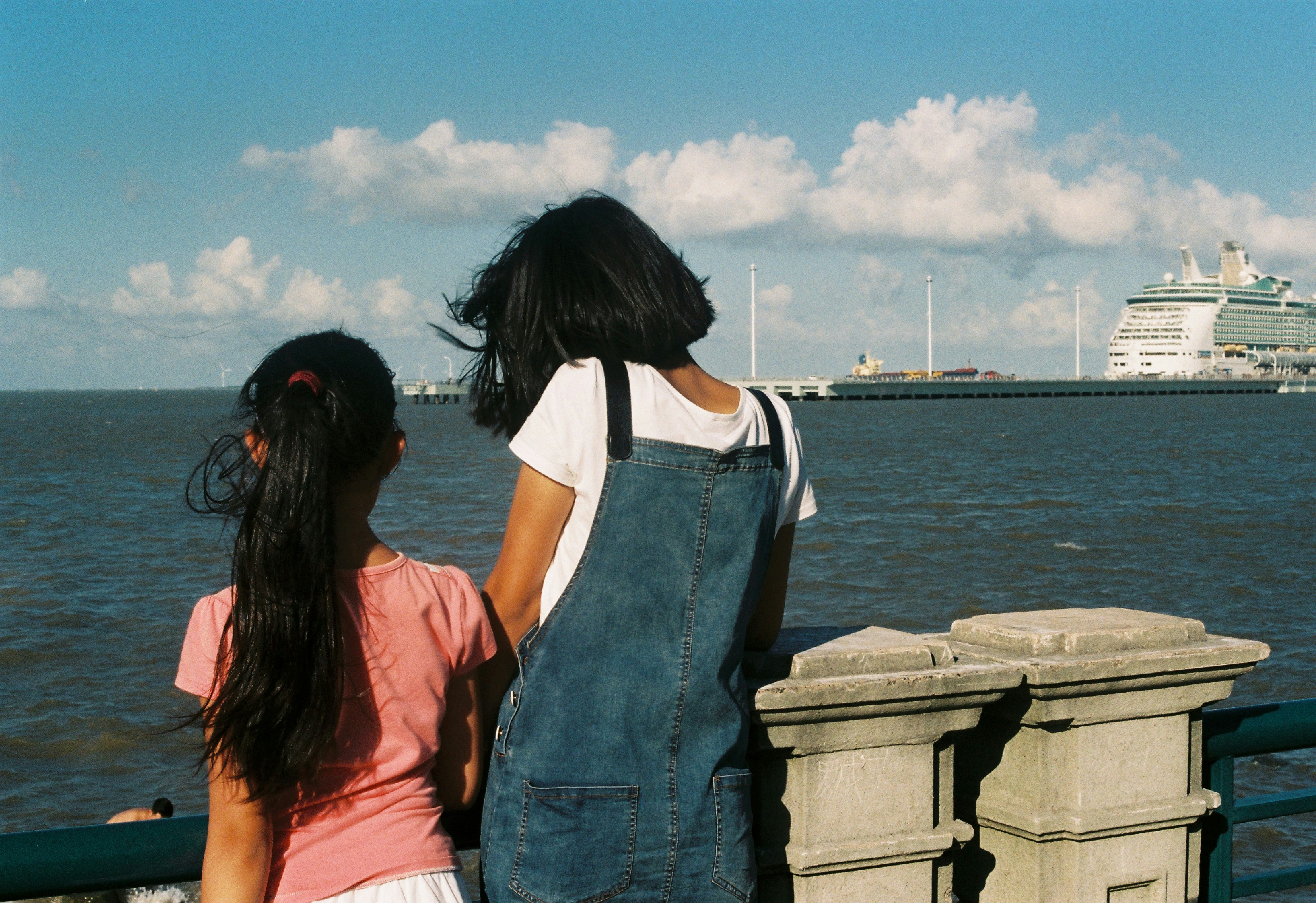 woman in blue denim dungaree standing beside woman in orange shirt