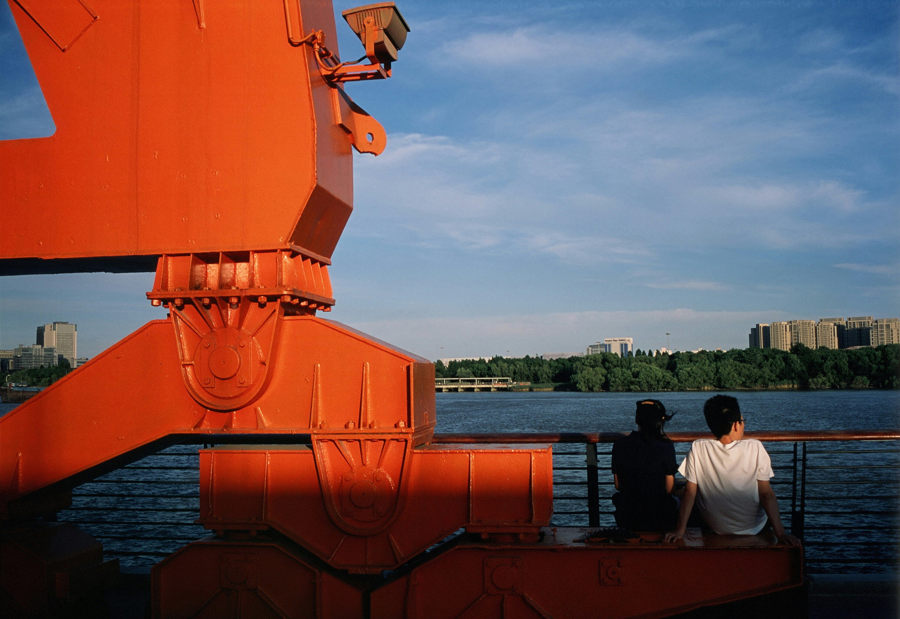 man in white t-shirt sitting on brown wooden dock during daytime