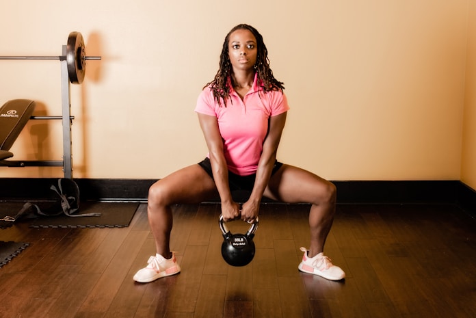 Black fitness trainer performing squats with weight