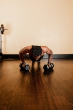 man in black tank top and black shorts holding black dumbbells