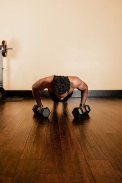 man in black tank top and black shorts holding black dumbbells