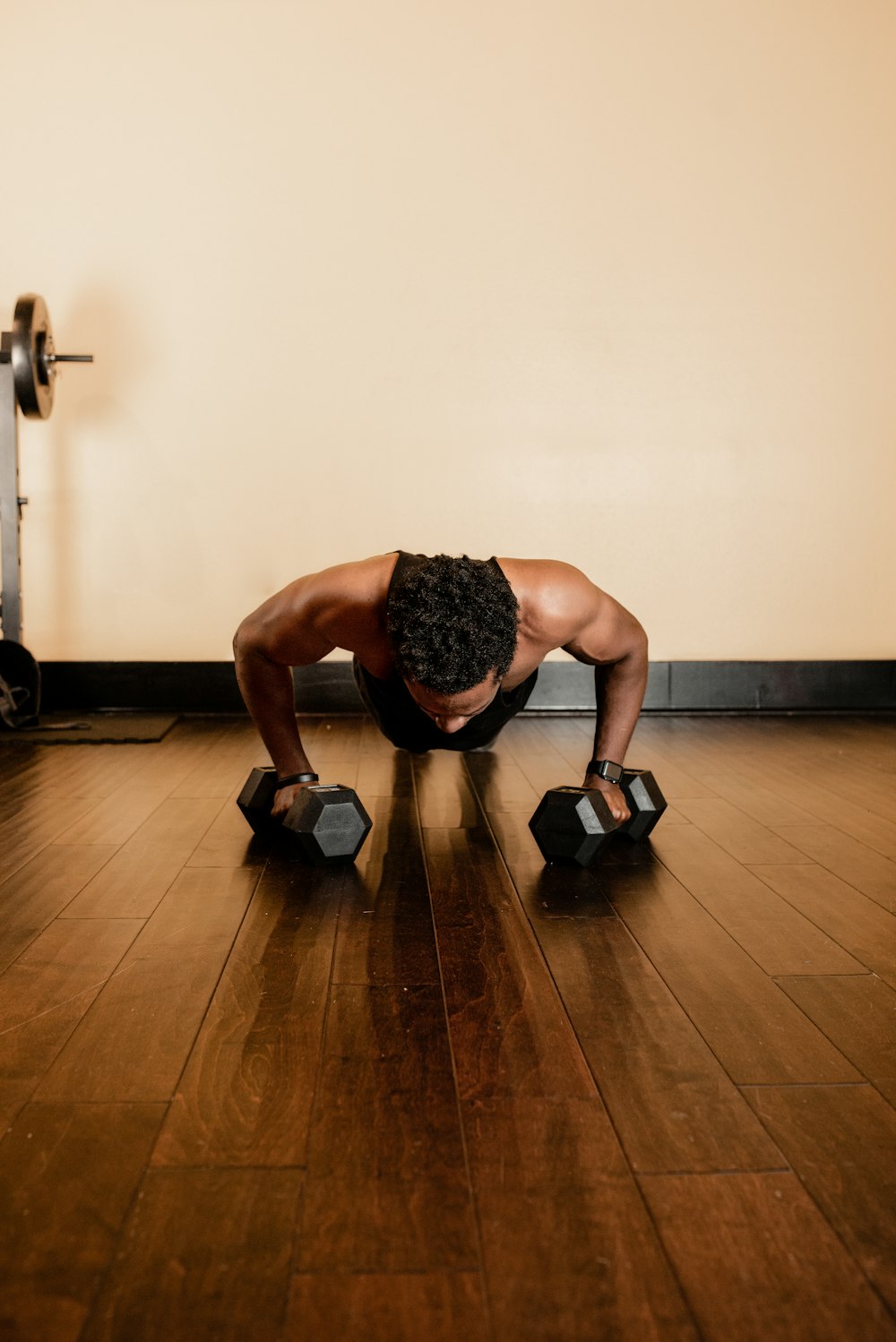 man in black tank top and black shorts holding black dumbbells