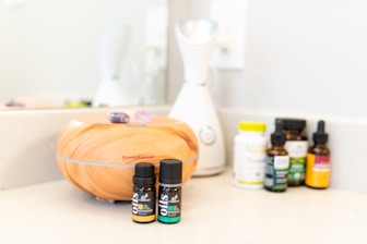 bottles of essential oils sit on a counter in front of a mirror