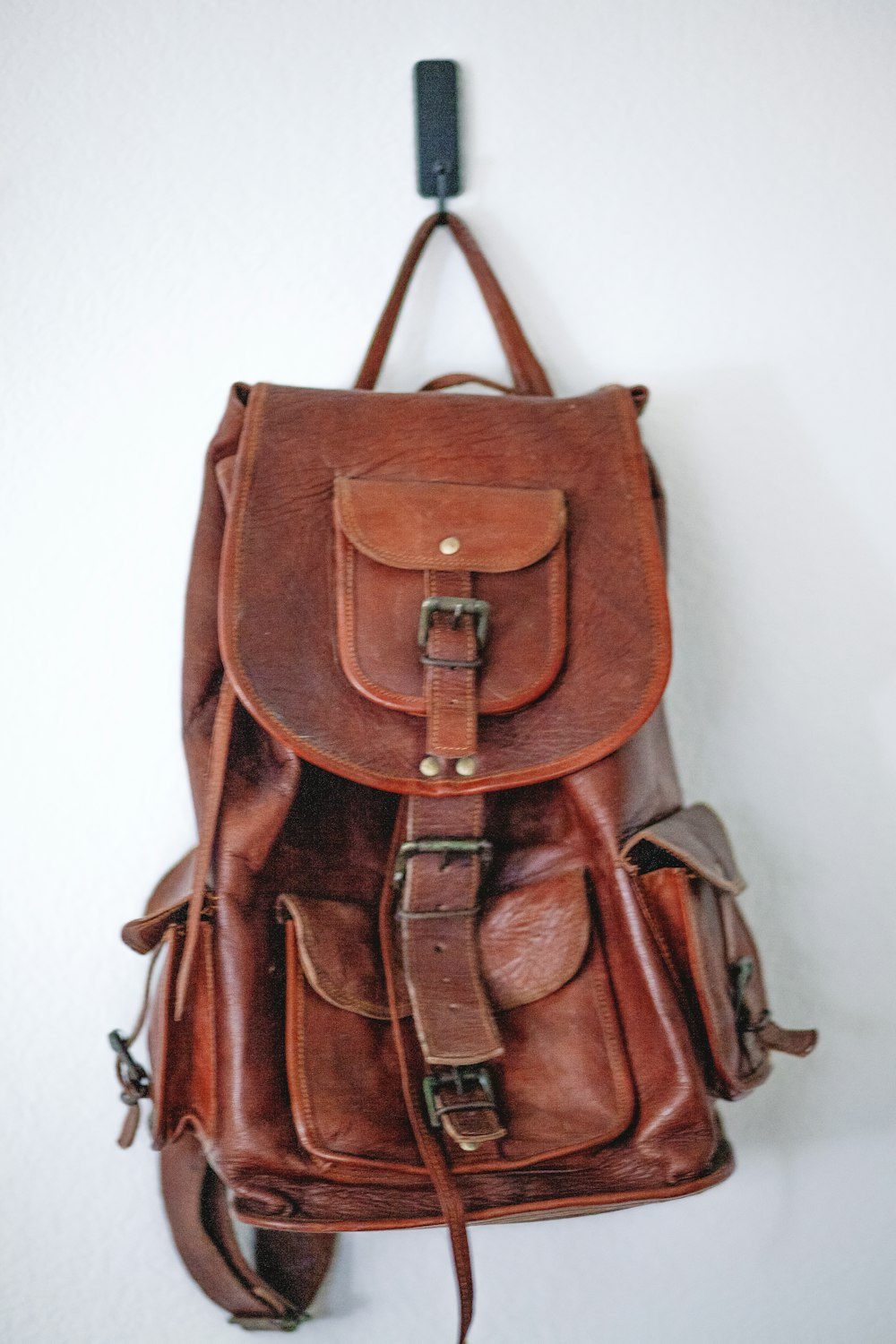 brown leather backpack on white wall