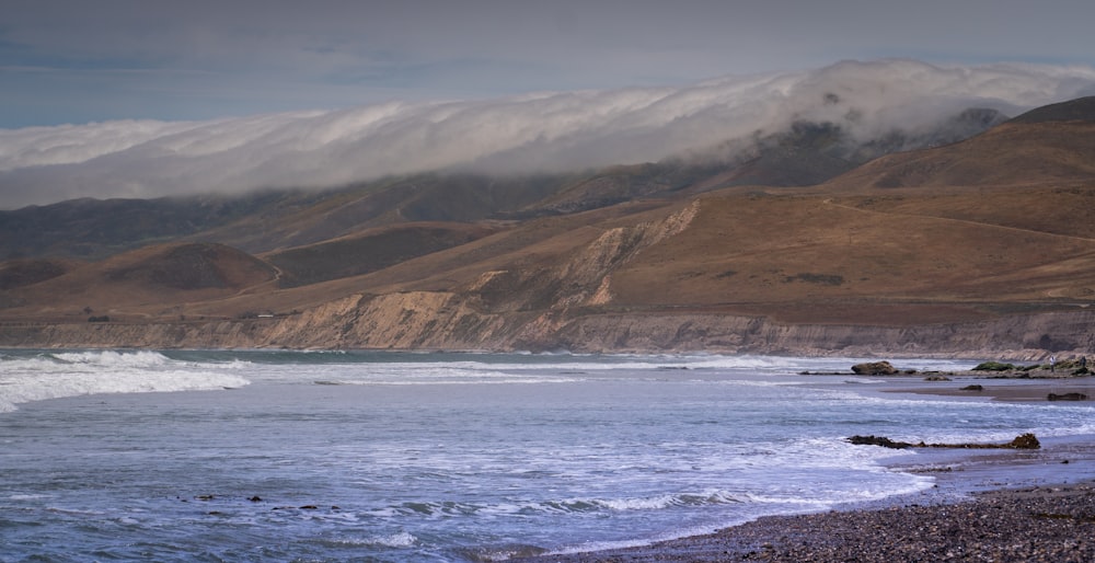 brown and green mountains beside sea during daytime