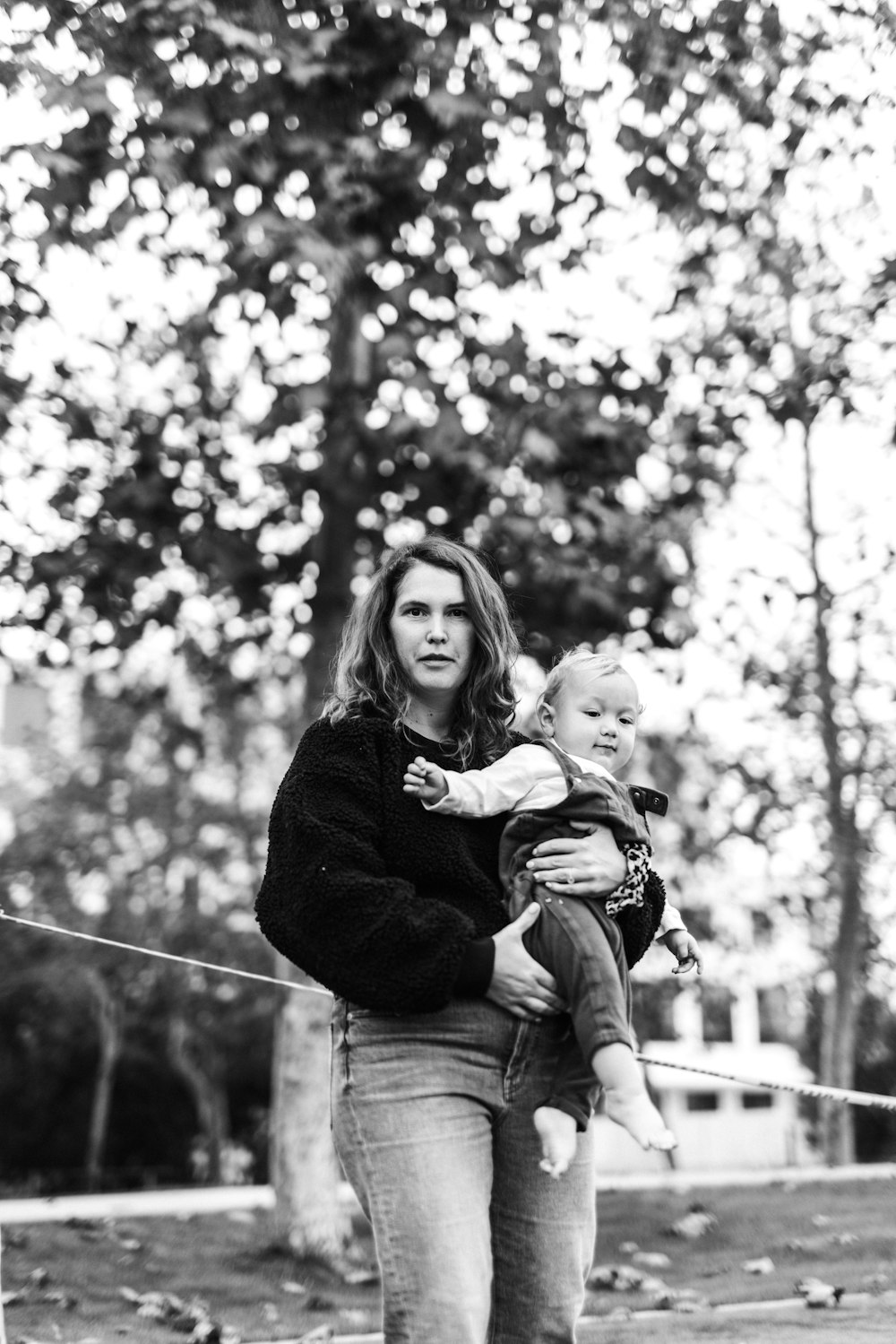 foto in scala di grigi della donna che trasporta il bambino