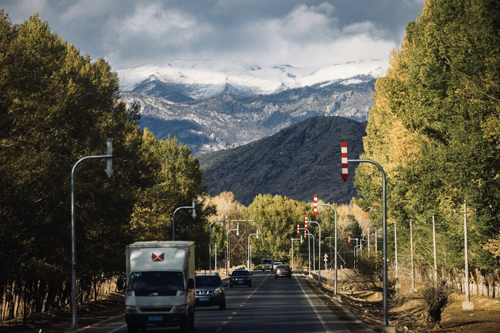 white van on road near green trees and mountains during daytime
