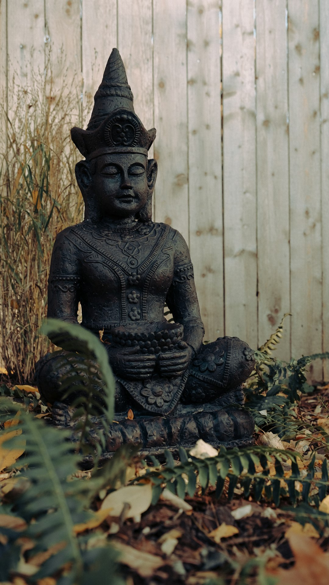 black buddha statue near brown wooden fence
